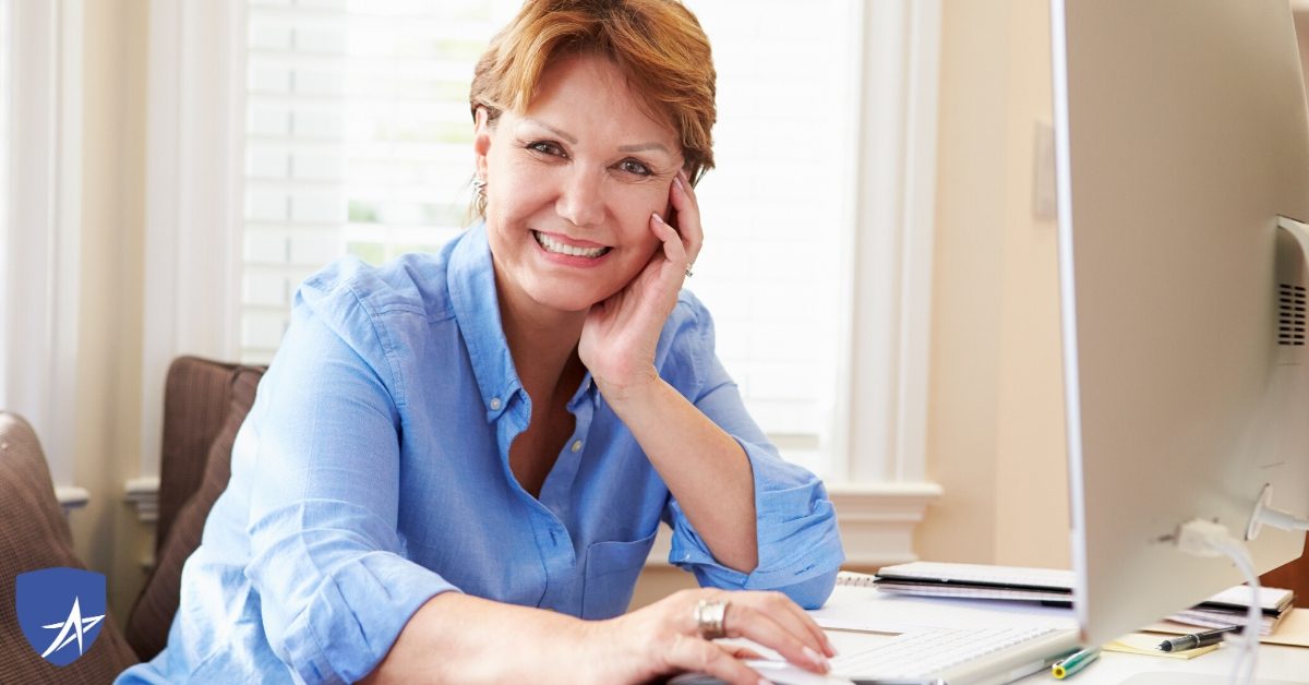 senior woman at computer smiling into camera